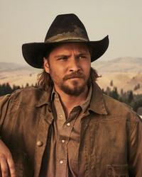 Luke Grimes leaning on Yellowstone fence