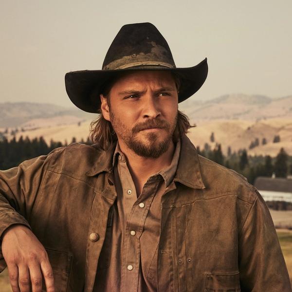 Luke Grimes leaning on Yellowstone fence
