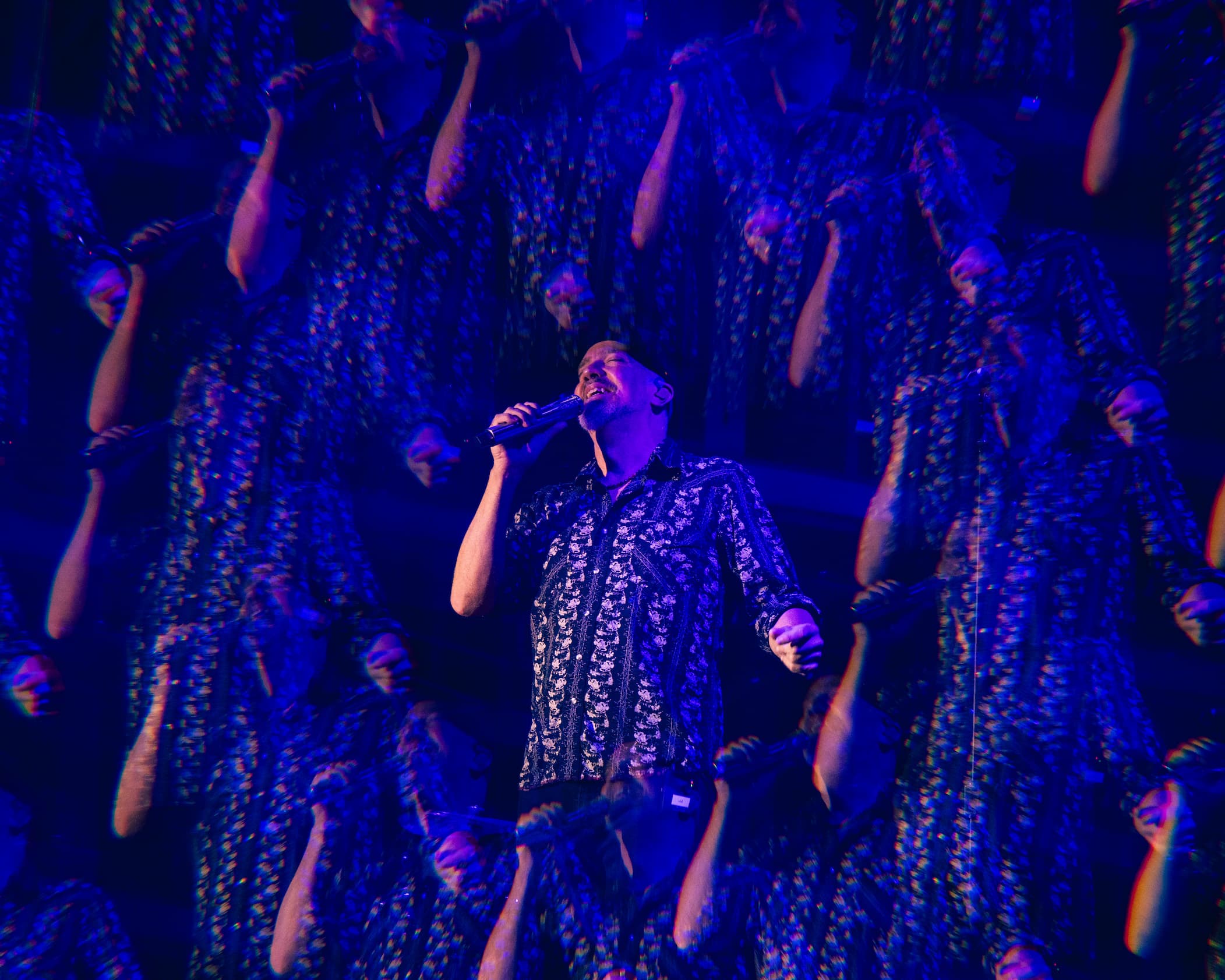 JJ Grey of Mofro singing into a microphone at night through the kaleidoscope lens of the camera at Orange Blossom Revue festival 2023.