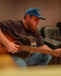 Luke Combs recording in a studio with a guitar