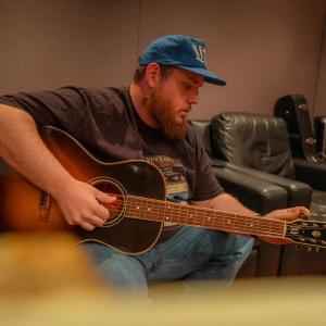 Luke Combs recording in a studio with a guitar