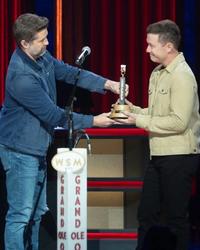 Scotty McCreery getting his Opry induction award from Josh Turner