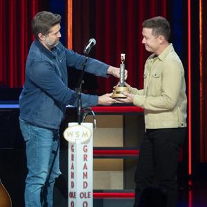 Scotty McCreery getting his Opry induction award from Josh Turner