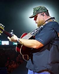Luke Combs performing with a camo hat