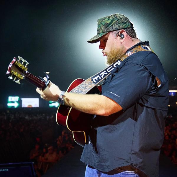 Luke Combs performing with a camo hat