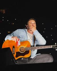 Zach Bryan holding his face on stage