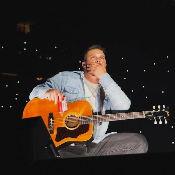 Zach Bryan holding his face on stage