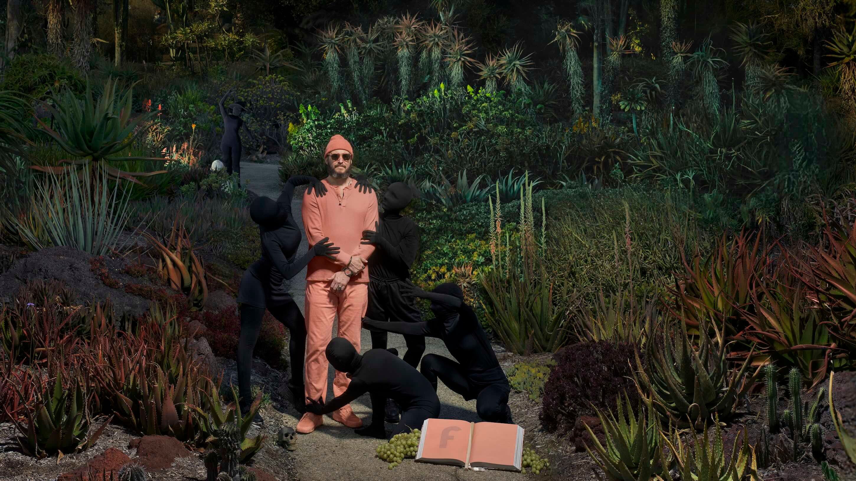 Bon Iver standing in a jungle with figurines holding him