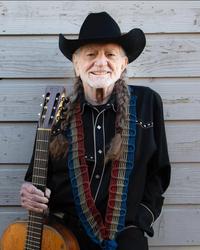 Willie Nelson smiling with his guitar