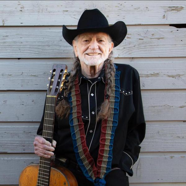 Willie Nelson smiling with his guitar
