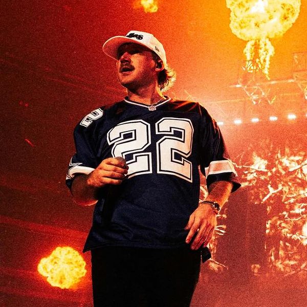 Morgan Wallen performing at AT&T Stadium with flames in the background.