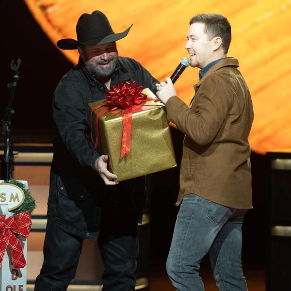 Scotty McCreery receiving a Christmas present from Garth Brooks on the Opry stage