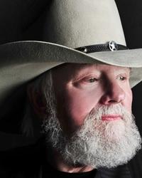 Charlie Daniels portrait, wearing a grey stetson cowboy hat and a black pinstriped jacket, looking to the right of the frame.