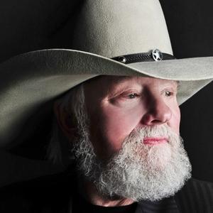 Charlie Daniels portrait, wearing a grey stetson cowboy hat and a black pinstriped jacket, looking to the right of the frame.