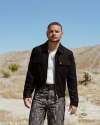 Kane Brown in the desert wearing a black jacket, white tee and pinstripe trousers.