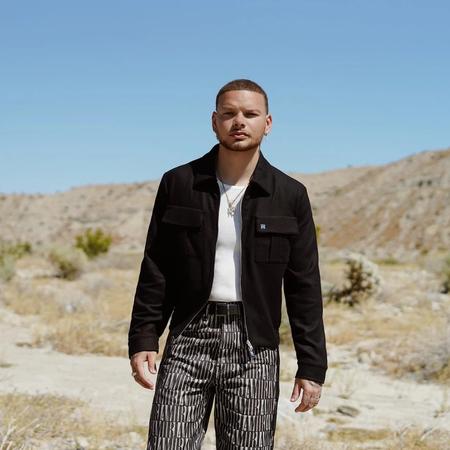 Kane Brown in the desert wearing a black jacket, white tee and pinstripe trousers.
