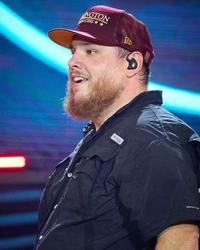 Luke Combs holding his hands up in the air on-stage