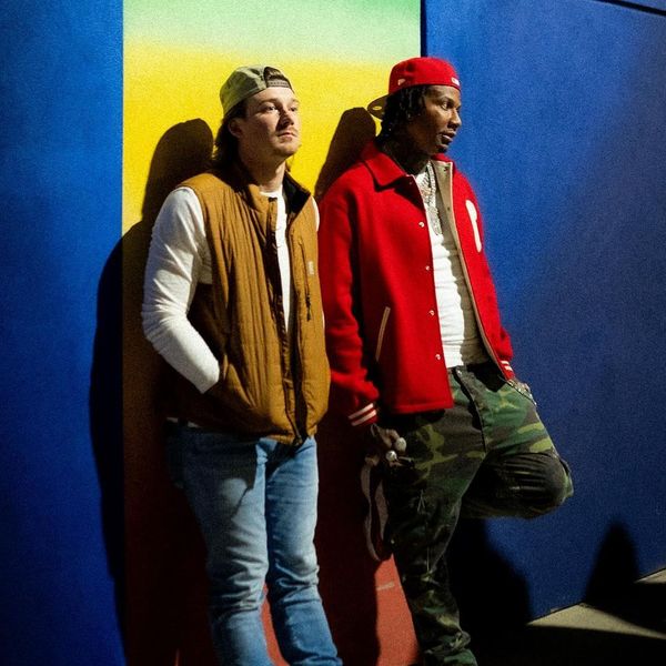 Moneybagg Yo and Morgan Wallen leaning against a brightly coloured wall