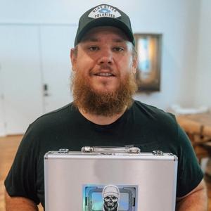 Luke Combs holding a briefcase