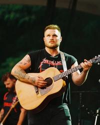 Zach Bryan performing on-stage in a Metallica tank-top