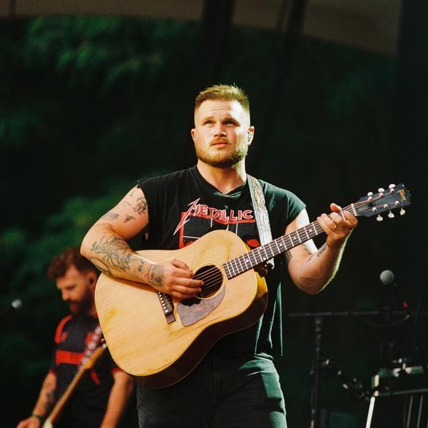 Zach Bryan performing on-stage in a Metallica tank-top