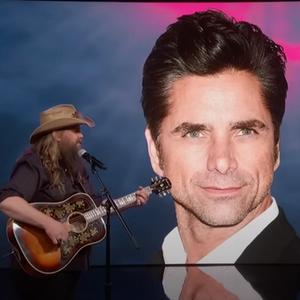 Chris Stapleton performing on Jimmy Kimmel with photo of John Stamos in the background