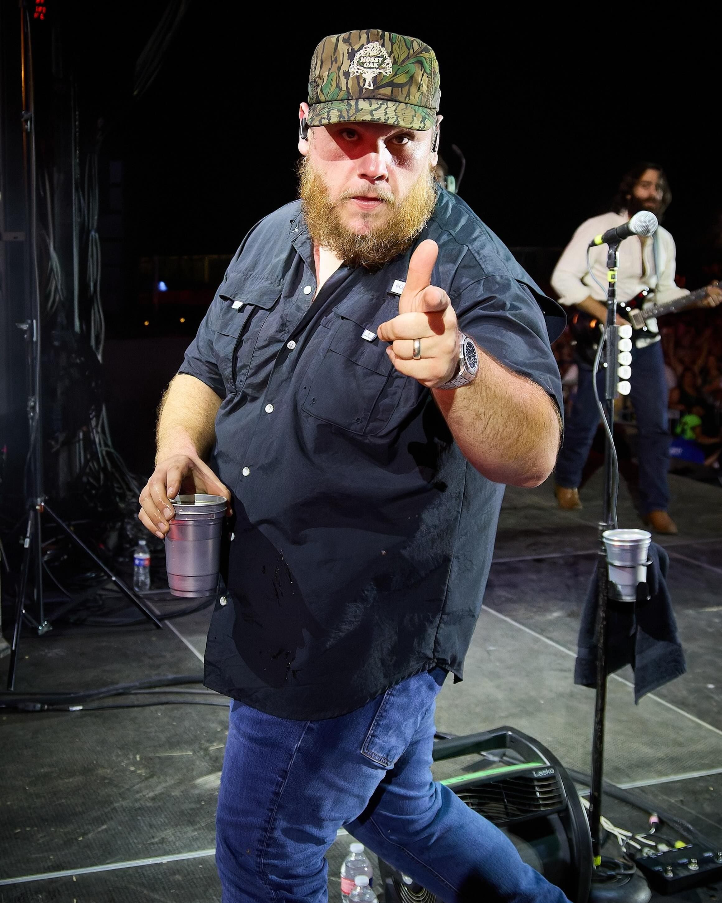 <p>Luke Combs wearing a camo hat backstage</p>