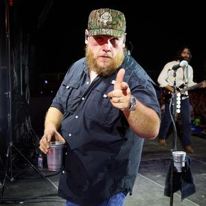 Luke Combs wearing a camo hat backstage