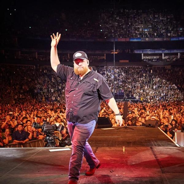 Luke Combs waving to a packed-out crowd as he exits the stage