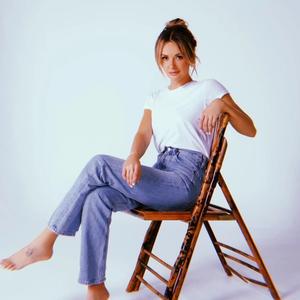 Carly Pearce sat on a stool against a white backdrop