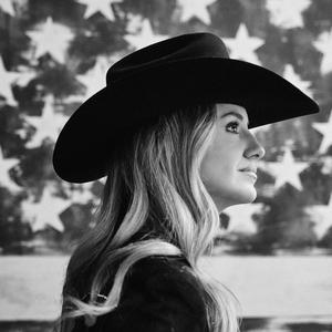Lainey Wilson black-and-white photo with American flag behind her