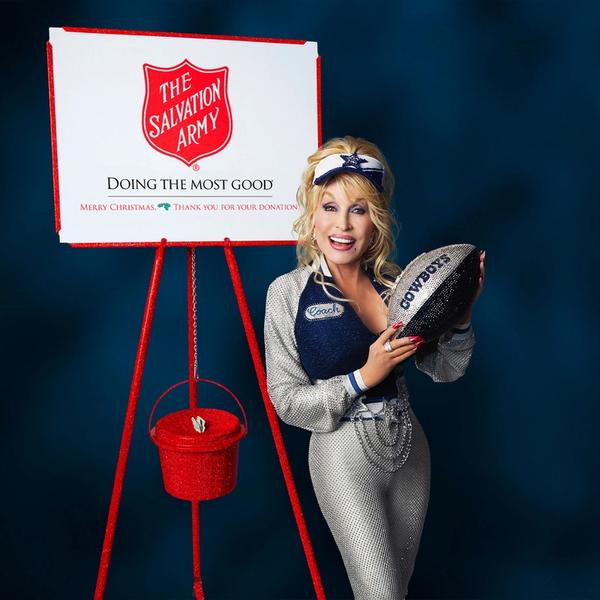 Dolly Parton holding an American football in front of a Salvation Army sign.