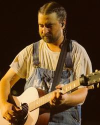 Noah Kahan looking down while performing
