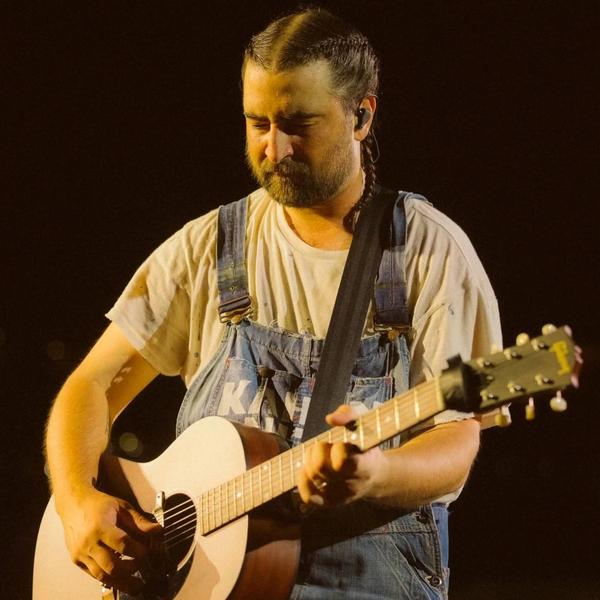 Noah Kahan looking down while performing