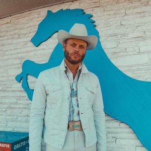 Charley Crockett standing in front of a blue horse decal on a wall 