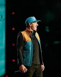 Morgan Wallen in a blue hat and blue gilet on-stage