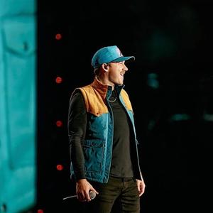 Morgan Wallen in a blue hat and blue gilet on-stage