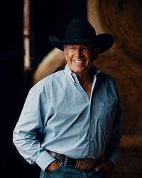 George Strait posing in front of haybales