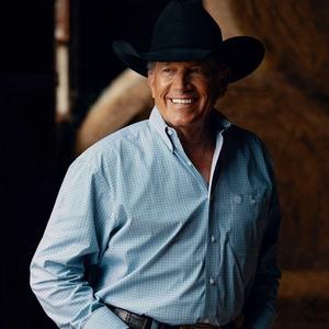George Strait posing in front of haybales