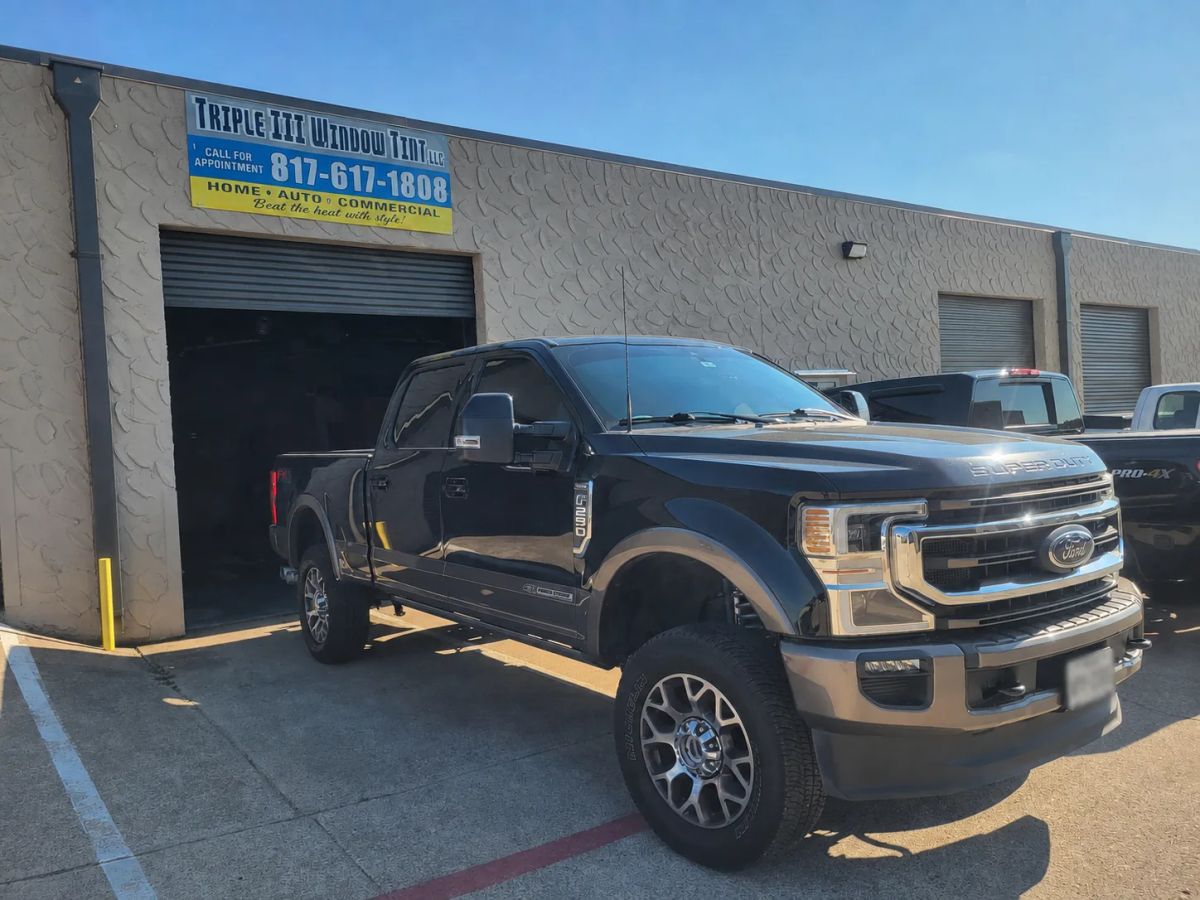 Dark Ford Super Duty pickup with tinted windows outside the Triple III shop
