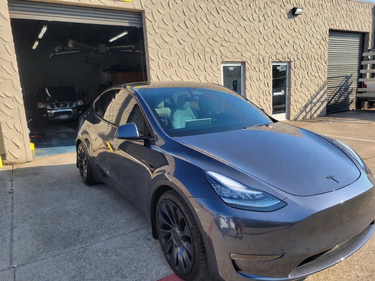 Dark gray Tesla crossover with tinted side windows outside the Triple III shop