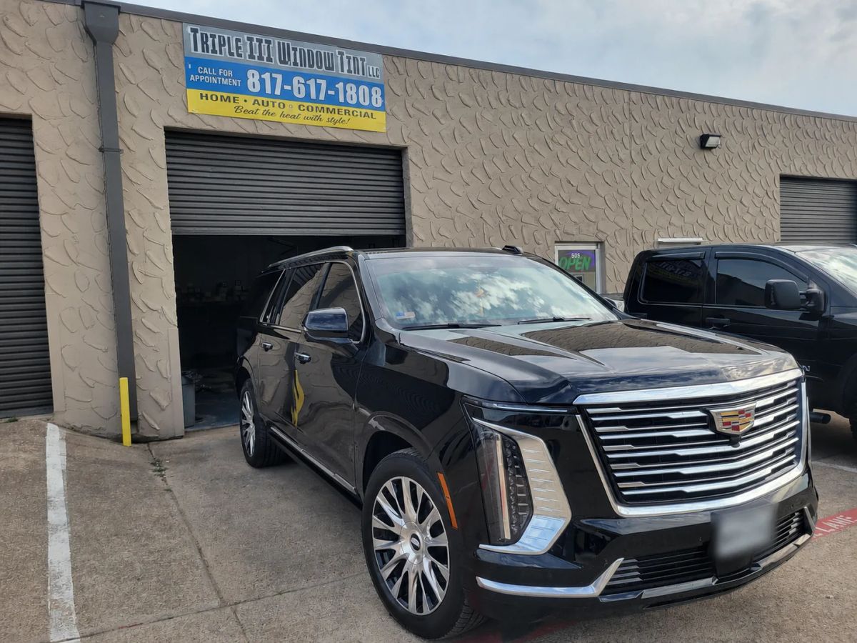 Black Cadillac SUV with tinted windows outside the Triple III shop