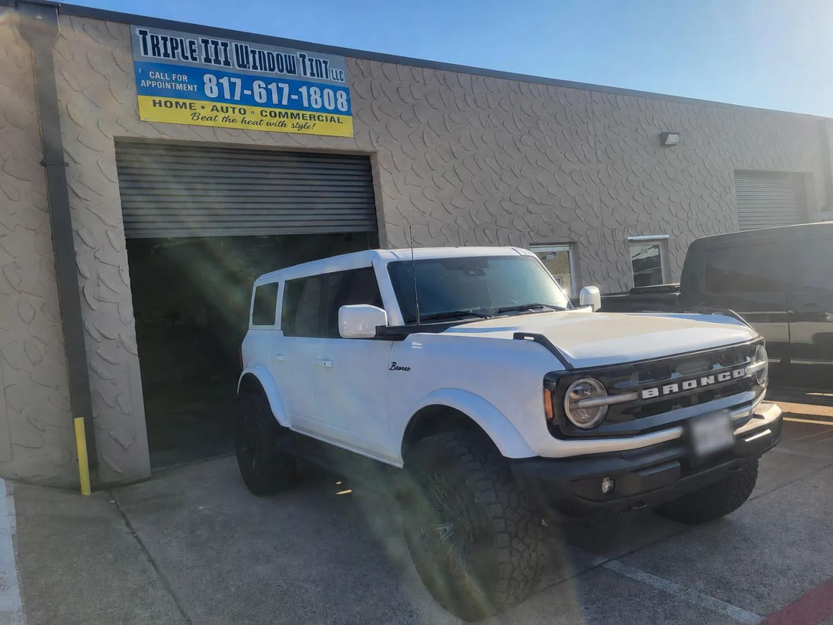 White Ford Bronco with dark window tint in front of the Triple III shop