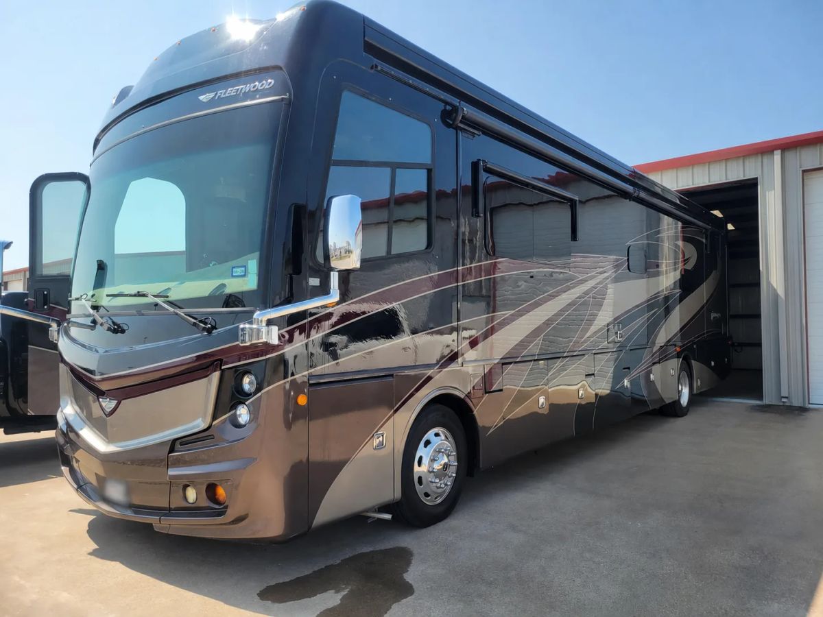 Large motor coach with tinted windshield and side windows in bright Texas sunlight