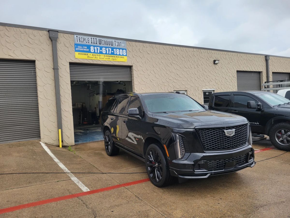 Black luxury SUV with tinted windows outside the Triple III shop after rainfall