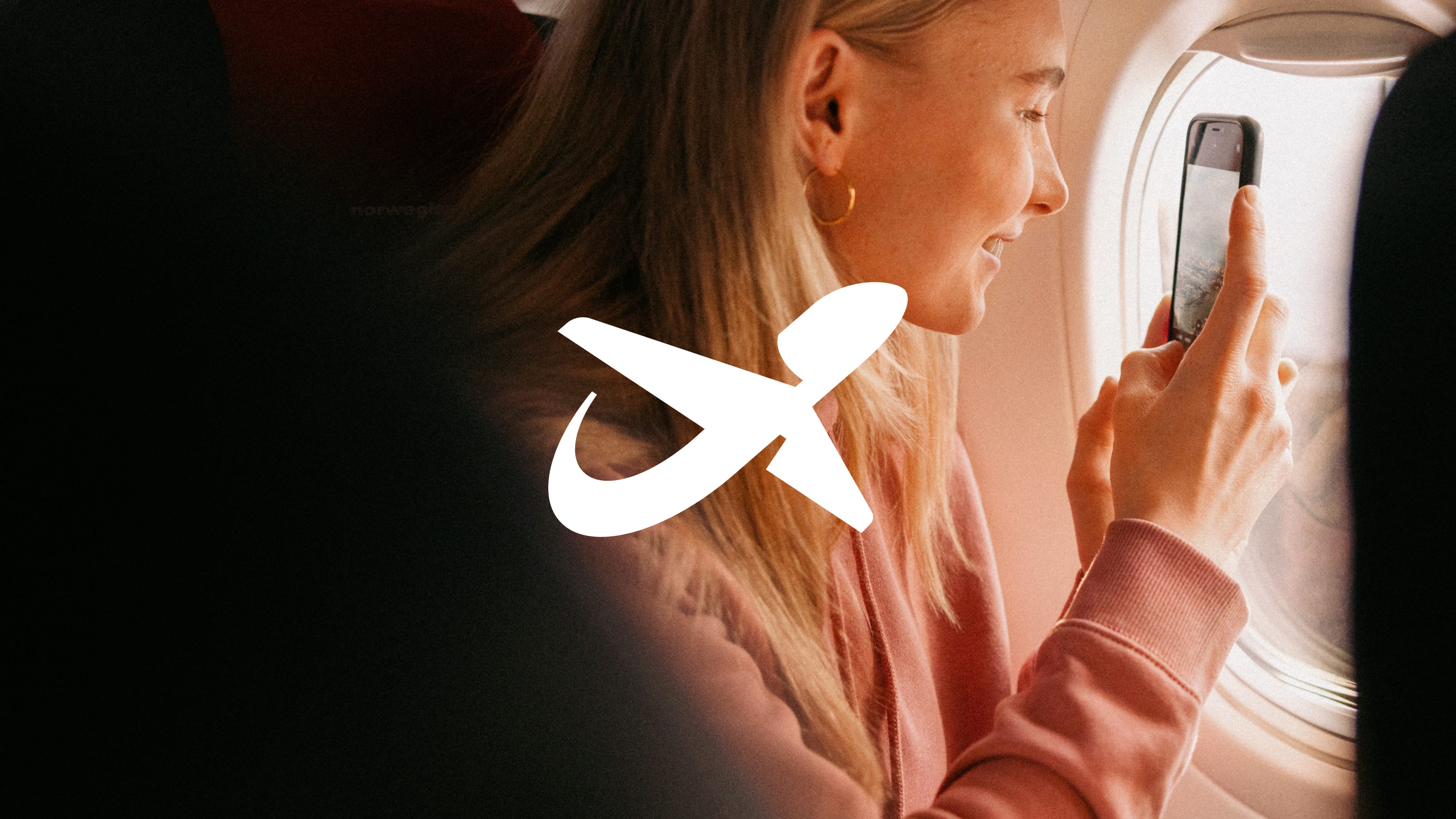 The white Norwegian tail-fin symbol over a photograph of a smiling passenger photographing the view from an aircraft window with her phone