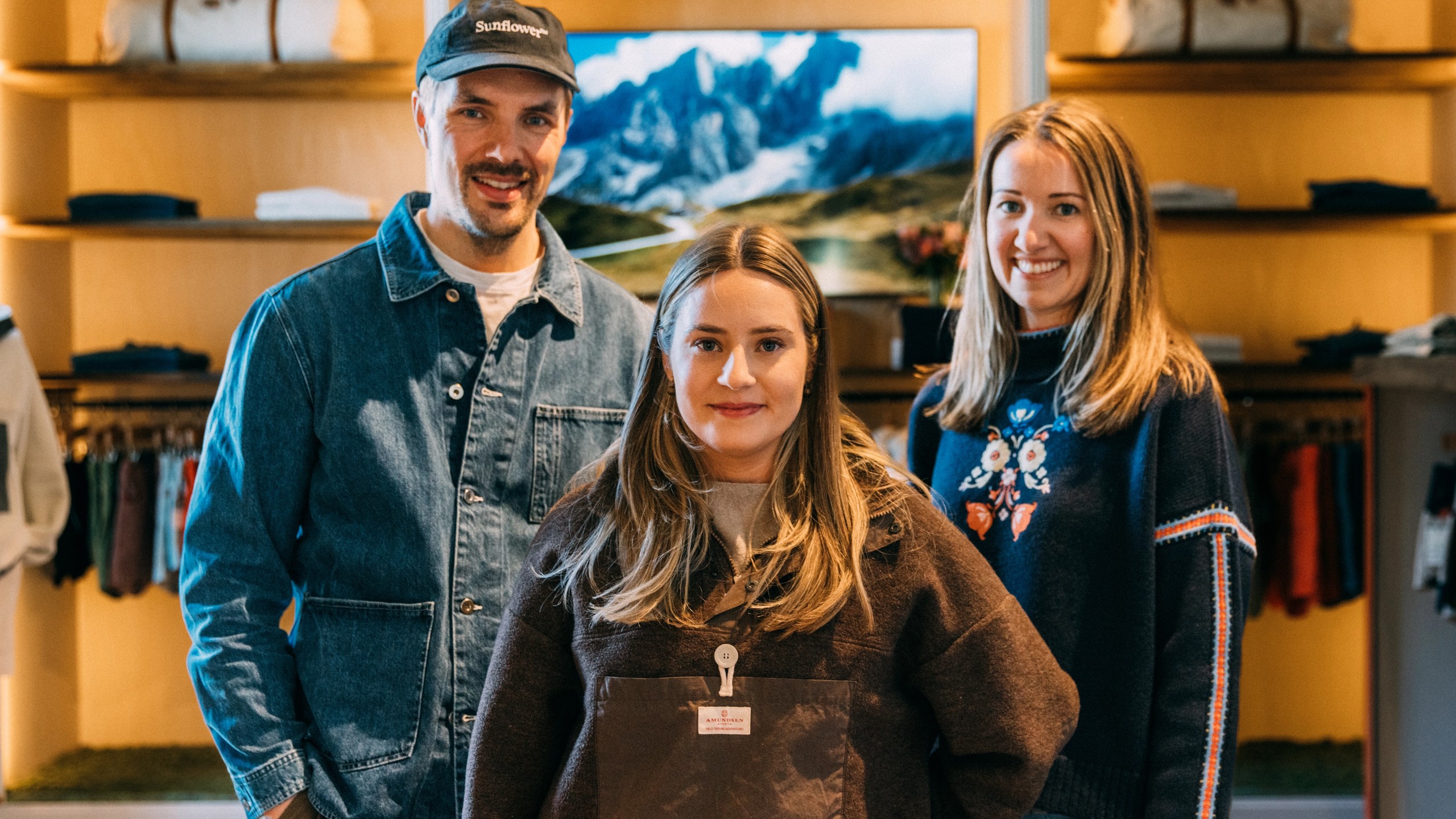 Dennis Nilsson fra TRY, Amalie Naustdal og Aurora Råken fra Amundsen smiler i en Amundsen-butikk.