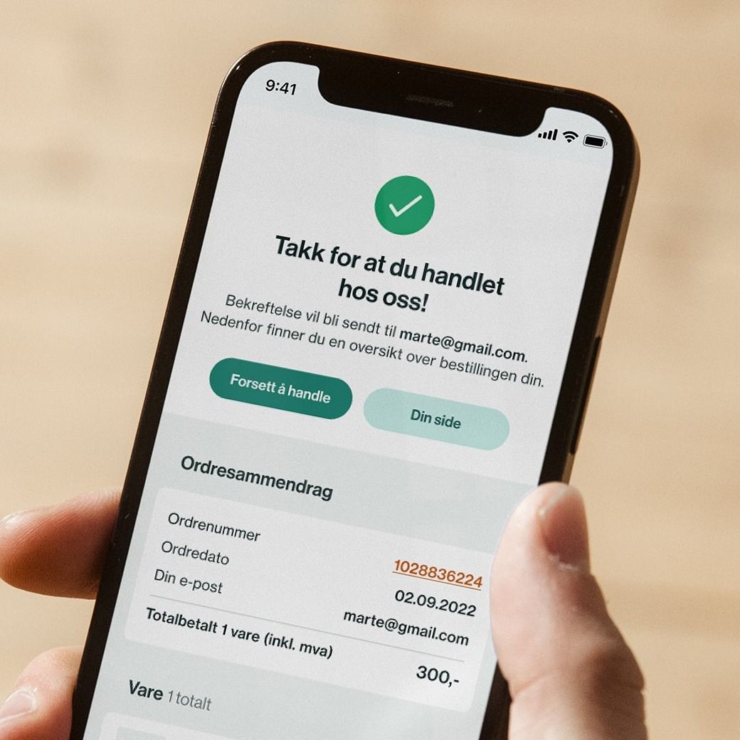 A hand holds a smartphone displaying a Norwegian e-commerce order confirmation screen.