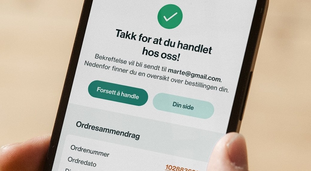 A hand holds a smartphone displaying a Norwegian e-commerce order confirmation screen.