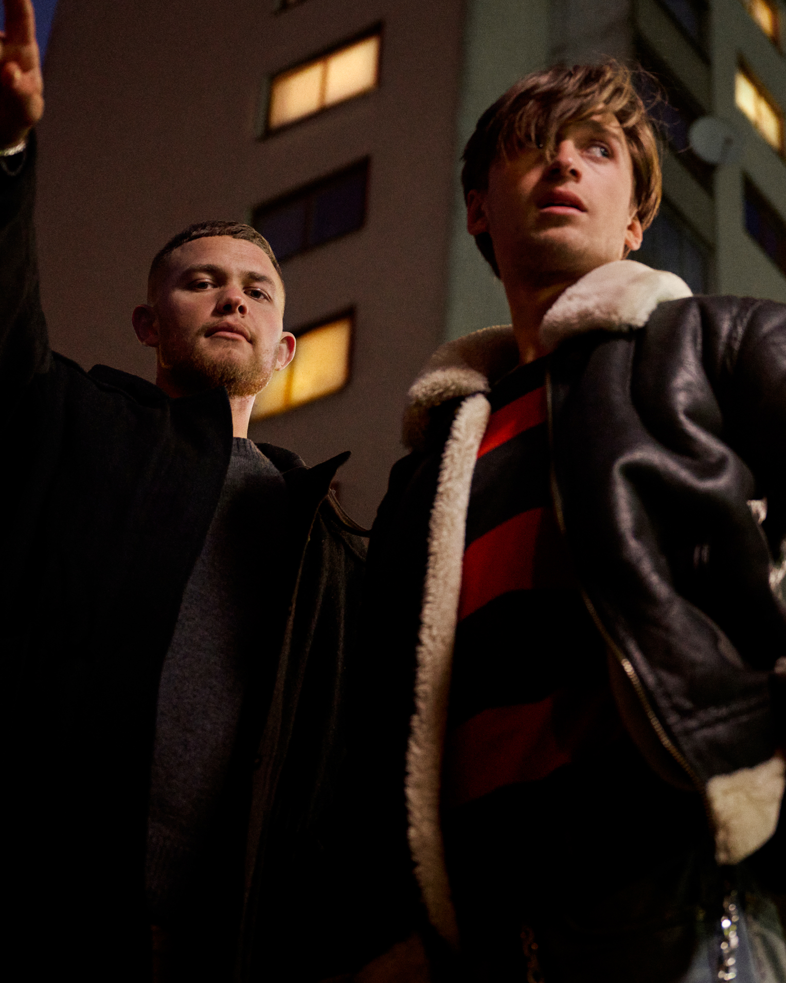 A production still of two young men on a bed, one lying down using a phone and the other sitting up looking at him, captioned "A series about drunkenness, betrayal & love" in orange type.